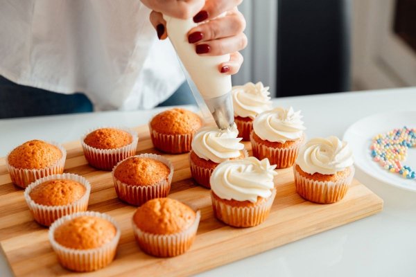 Lady icing cupcakes with piping bags